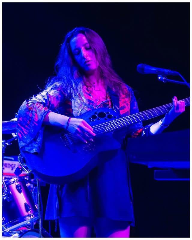 Penumbra vocalist performing live with acoustic guitar under stage lighting